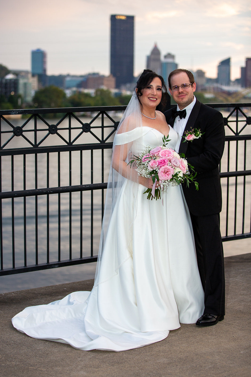 Pittsburgh Wedding couple standing on a bridge with a city skyline in the background