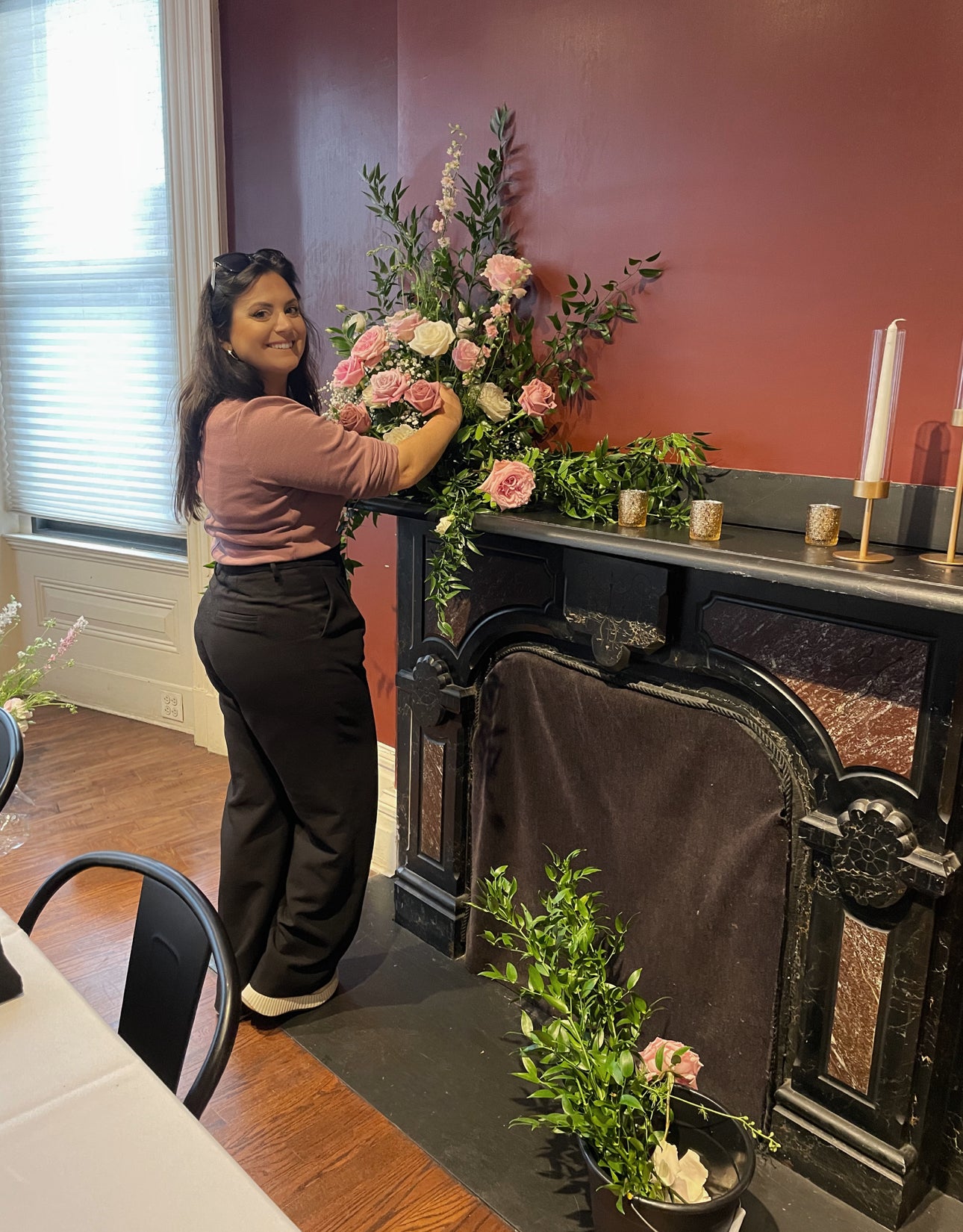 Sophia arranging flowers in a decorative setting with candles and plants.